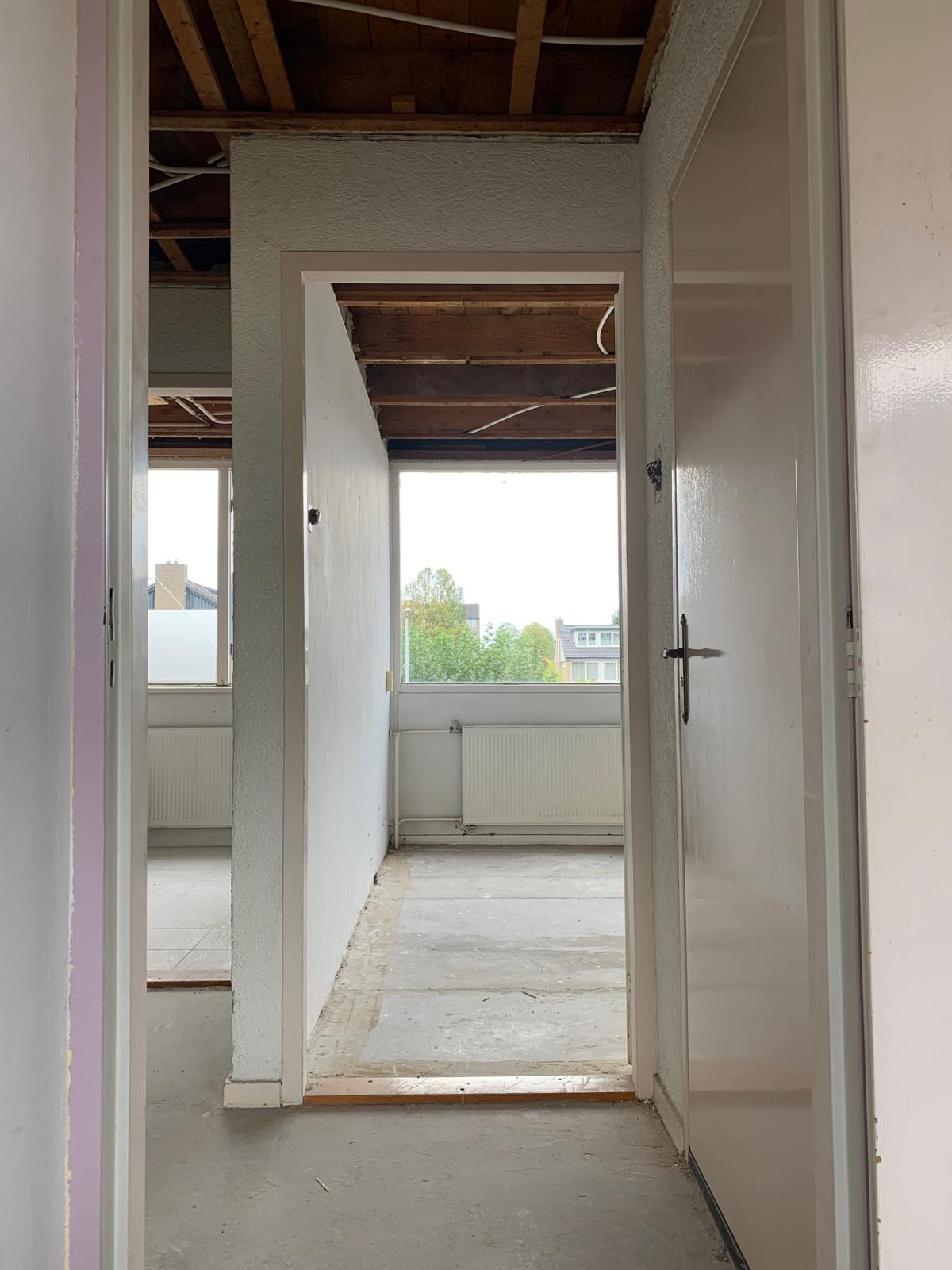 Dezelfde kamer met het plafond volledig verwijderd, open balklaag en een schone vloer