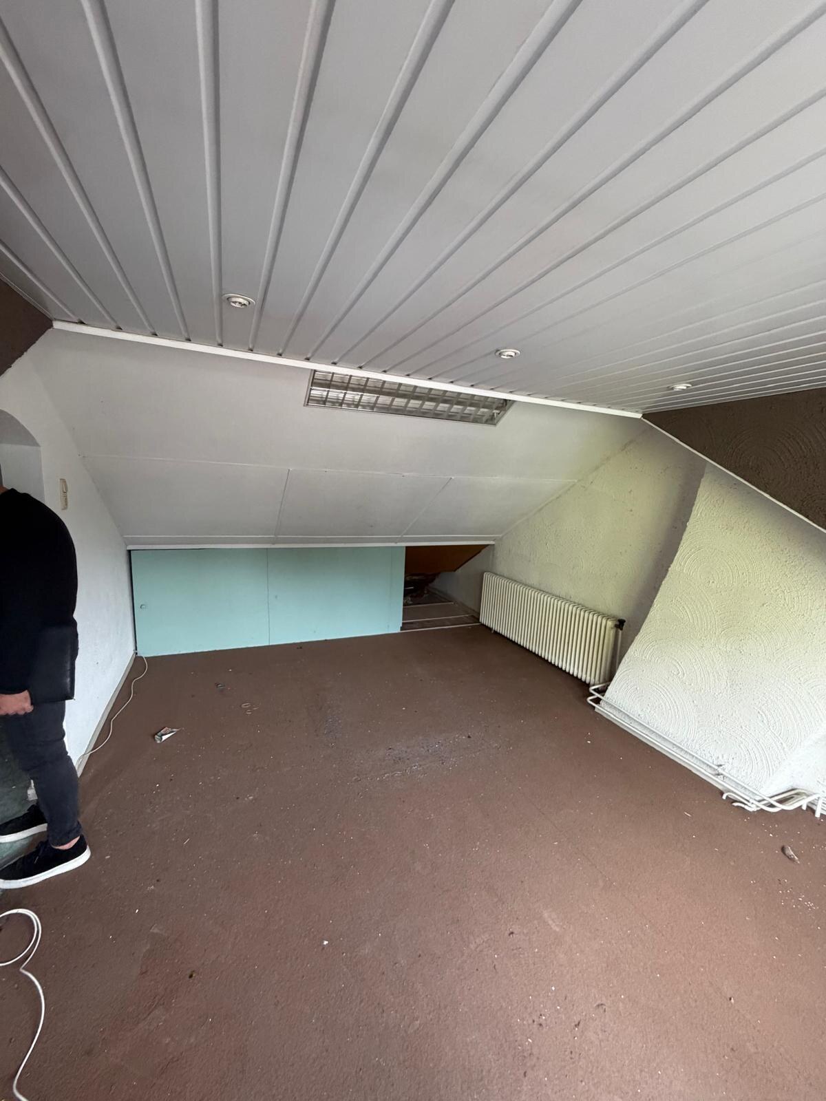 Zolder met wit schrootjesplafond, lichtgroene wand en bruine vloerbedekking, voor het strippen